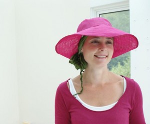 Big brimmed pink hat worn with chemo bandana underneath