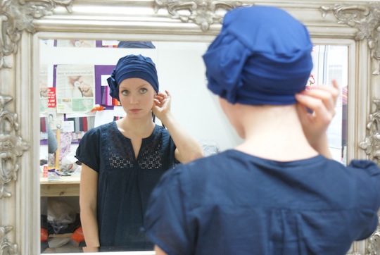 model looking at her reflection in the mirror wearing a blue hat