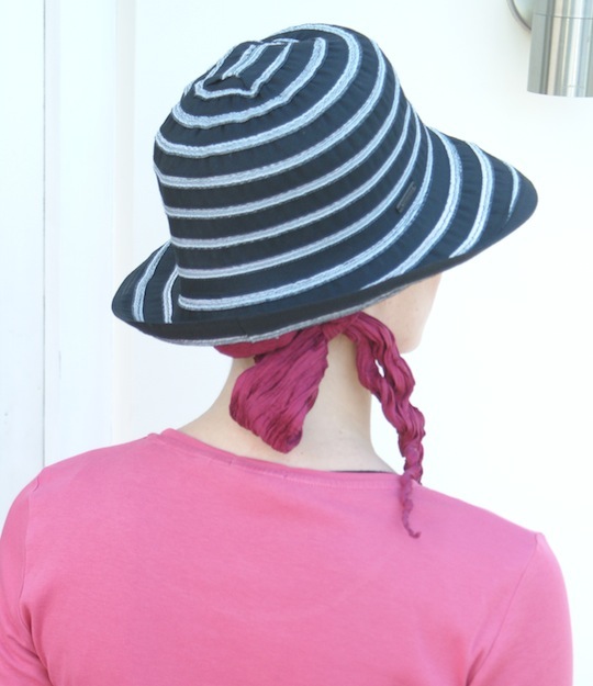 back view of black summer hat worn over pink head scarf