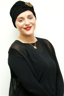 Classic black evening turban worn with gold brooch