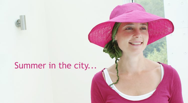 woman wearing pink big brimmed summer hat with chemo headscarf underneath