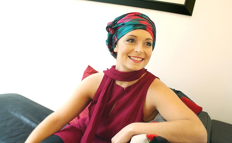 Young woman wearing evening chemo headscarf on sofa