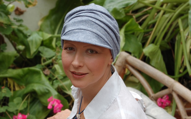 woman seated in garden wearing chemo cap