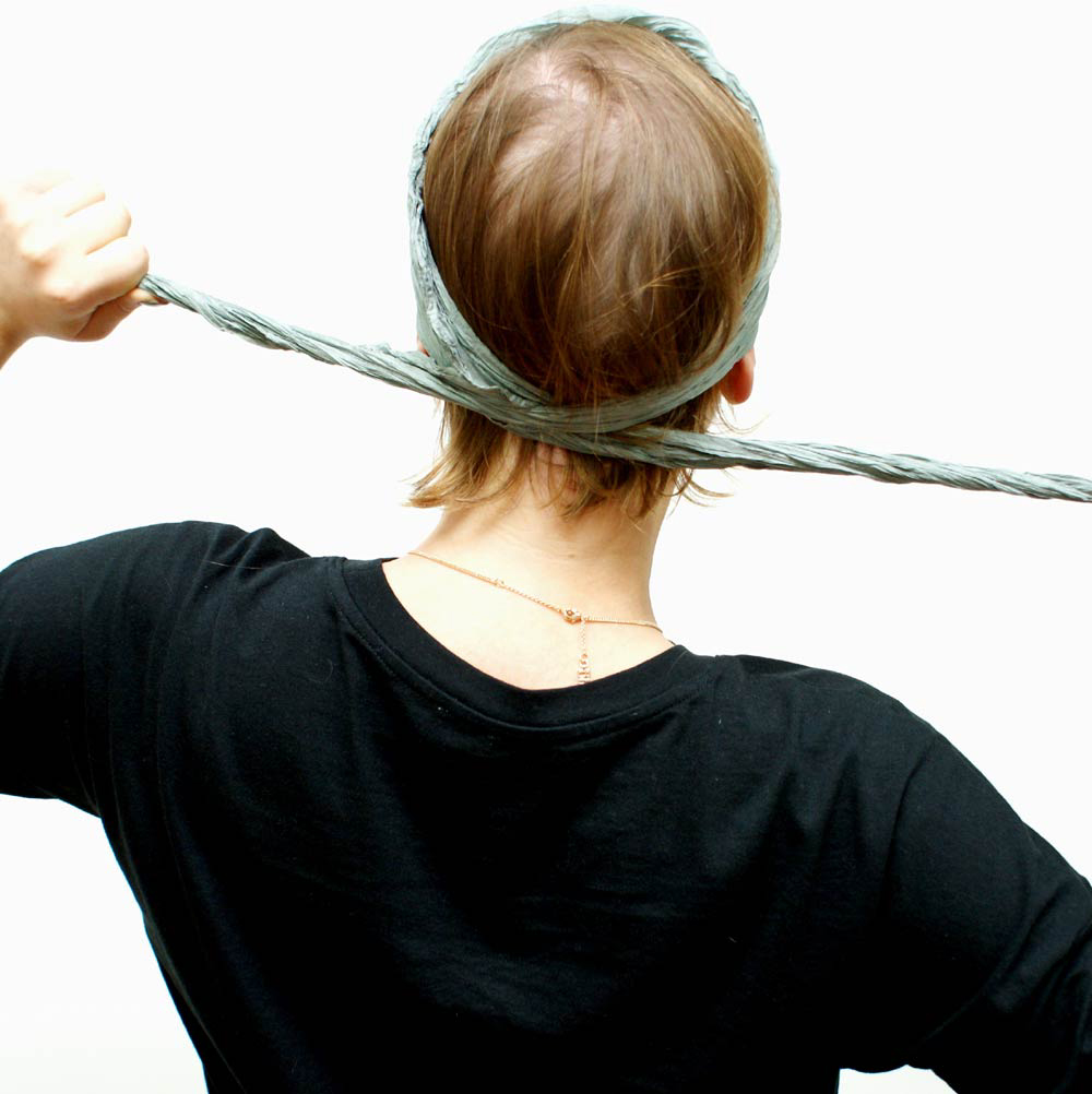 Crossing the ends of a silk headband scarf at the back of the head