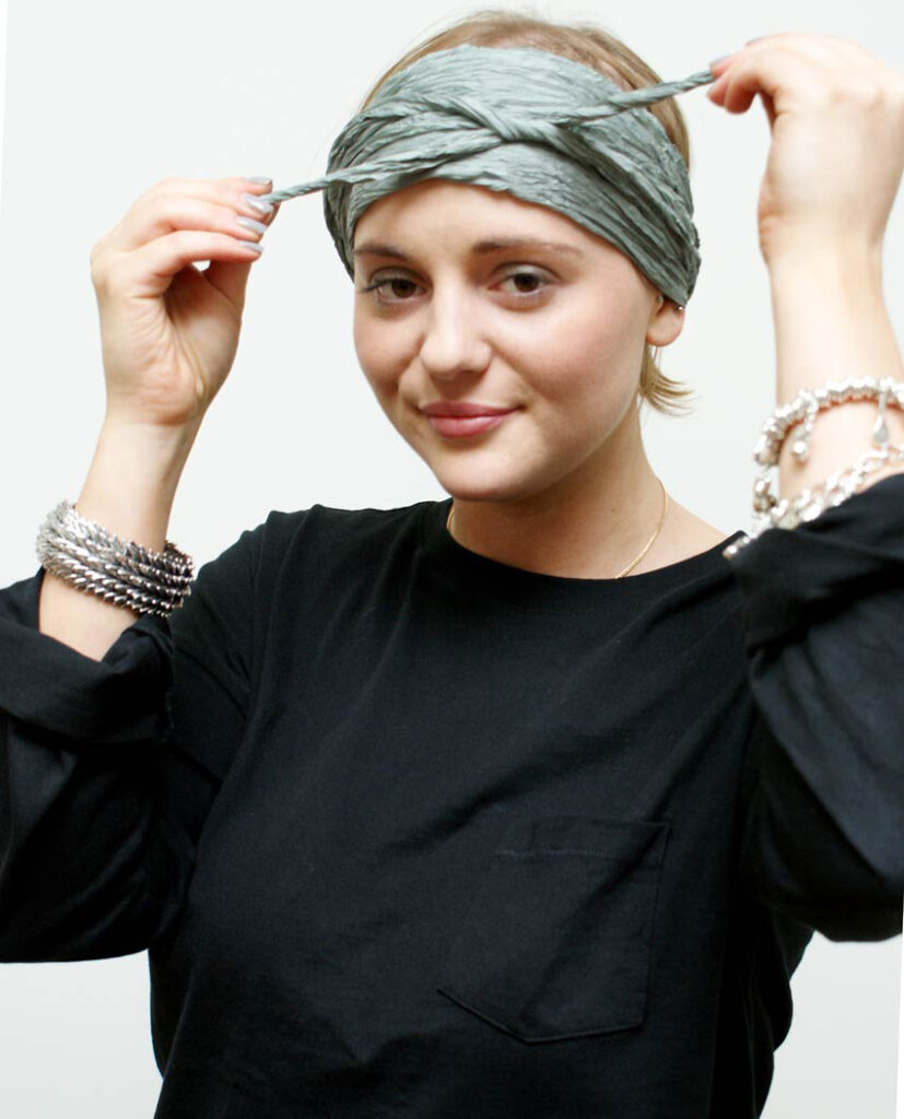 Tying a silk headband scarf at the forehead with a small knot to one side